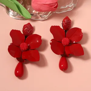 Detailed view of vibrant red metal flower earrings featuring smooth teardrop pendants