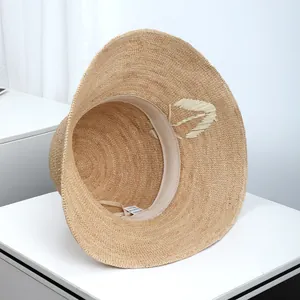 Detailed interior view of a wide-brimmed raffia straw sun hat with an internal sweatband
