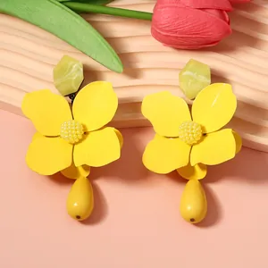 Detailed close-up of oversized matte yellow flower earrings with elegant drop pendants