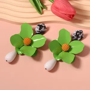 Close-up detail of vibrant green metal flower earrings featuring white teardrop pendants