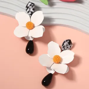 Detailed view of fashion metal flower earrings featuring black water drop pendants
