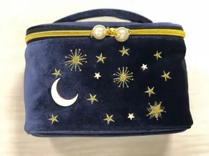 Nahaufnahme einer luxuriösen dunkelblauen Samt-Kosmetiktasche mit goldener Stern- und Mondstickerei