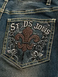 Detail view of vintage blue flared jeans featuring heavy embroidery on the back pocket