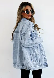 Close-up of a light wash distressed denim jacket worn by a stylish woman in sunglasses