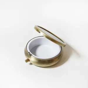 Vue détaillée d'une boîte à pilules ronde en métal ouverte avec miroir intérieur pratique