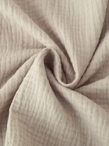 Macro view showing the soft beige double-layer cotton gauze fabric texture of the vest