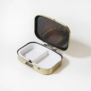 Vue détaillée d'un pilulier métallique portable avec deux compartiments blancs et fini bronze