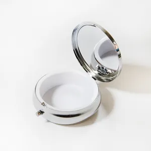 Vue détaillée d'une boîte à pilules ronde portable en métal argenté avec miroir intérieur