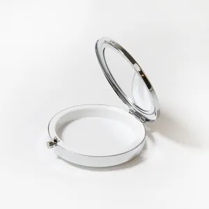 Vue détaillée du miroir intérieur et de la doublure blanche d'un pilulier rond en métal argenté