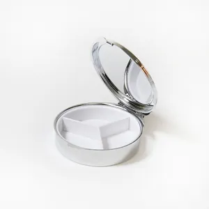 Vue détaillée du pilulier rond en métal montrant trois compartiments et un miroir