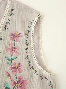 Close-up detail of vintage pink floral cross-stitch embroidery on a textured grey vest