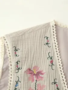 Detailed view of floral embroidery and crochet lace trim on a vintage vest jacket