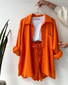 Detail of orange crinkle fabric two-piece shirt and drawstring shorts set for women.