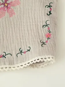 Detailed macro view of delicate floral cross-stitch embroidery and lace trim on vintage vest