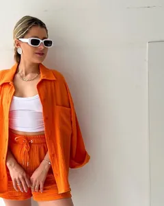 Trendy orange crinkle fabric two-piece set featuring long sleeve shirt and high waist shorts