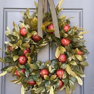 Close-up detail of a handmade autumn pomegranate wreath with realistic fruits and leaves