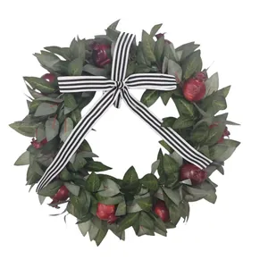 Close-up detail of artificial pomegranate fall wreath featuring a striped ribbon bow accent