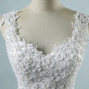 Close-up of intricate lace and pearl detailing on a white V-neck wedding dress bodice.