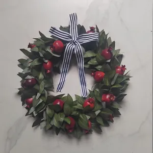 Autumn wreath with red pomegranates and striped bow for wall decoration
