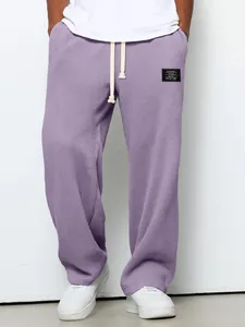 Nahaufnahme der lila Waffelstrick-Herrenhose mit dekorativem schwarzem Etiketten-Patch.
