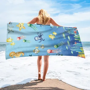 Model showing a blue microfiber beach towel with cute sea creature prints on the beach