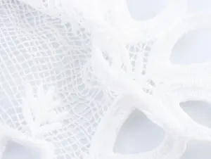 Close-up detail of white water-soluble lace embroidery on a French style shirt