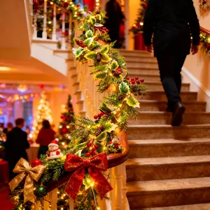 Detailansicht der festlichen künstlichen Weihnachtsgirlande mit warmen LED-Leuchten auf Treppe