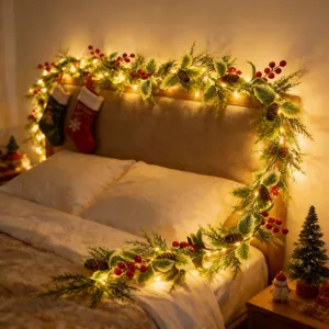 Detail einer festlichen Weihnachtsgirlande mit LED-Lichtern und roten Beeren auf dem Bett