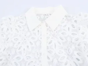 Detailed macro view of white water-soluble floral embroidery on a lace shirt collar.