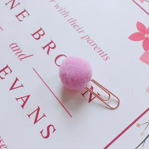 Close-up of a cute pink pom-pom paper clip on a decorative floral background card