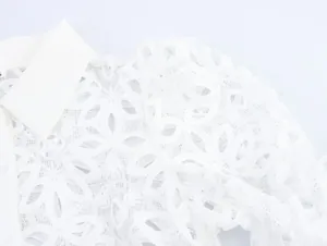 Detailed close-up of intricate white water-soluble lace and embroidery on a chic shirt collar