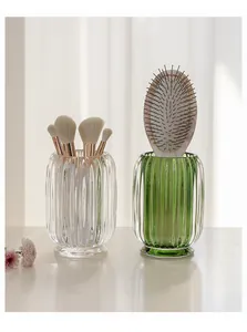 Elegant ribbed glass makeup brush holders in clear and green finishes for a vanity setup