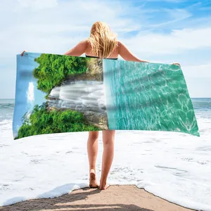 Detail of a microfiber beach towel with a waterfall print shown at a sunny beach.
