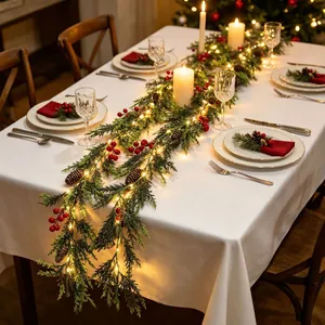 Festliche LED-Weihnachtsgirlande mit Tannenzapfen und roten Beeren auf dem Esstisch