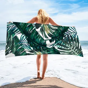 Detail of microfiber beach towel featuring vibrant green tropical leaf patterns