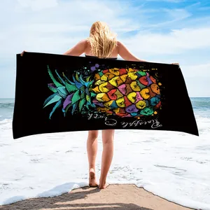 Lifestyle detail showing a woman holding a black beach towel with a colorful pineapple.