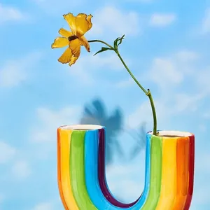 Detail der U-förmigen Regenbogen-Vase mit gelber Blume vor blauem Himmel