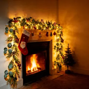 Detailansicht der Weihnachts-Eukalyptus-Girlande mit warmen LED-Lichtern am gemütlichen Kamin