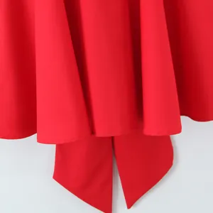 Detail of a bright red mini dress featuring a large back bow and elegant ruffled hemline