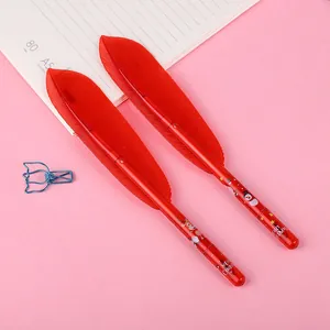 Close-up of red feather pens with festive Christmas prints on pink background