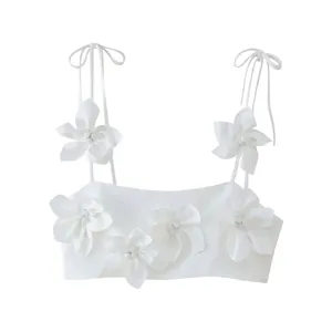 Front view of a white cropped camisole top featuring large 3D floral decorations.