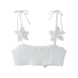 Detailed view of white crop top with 3D flower accents and smocked back panel