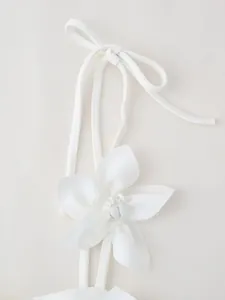 Detailed close-up of a decorative white fabric flower on a stylish crop top strap.