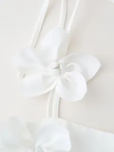 Macro view of the elegant handcrafted white fabric flower decoration on crop top