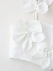 Close-up detailed view of 3D white fabric flower appliques on a minimalist crop top