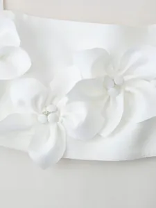 Close-up detail showing intricate 3D fabric flowers on a white minimalist crop top