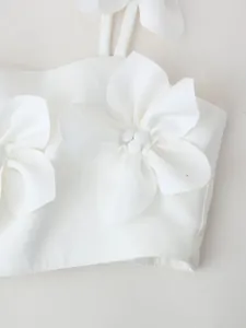 Close-up detail of a white crop top featuring elegant 3D fabric flower decorations