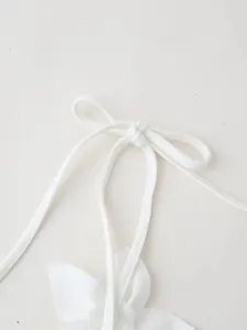 Elegant close-up of white bow tie-up strap and 3D floral decoration on stylish crop top