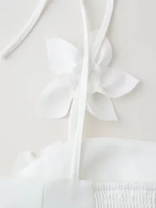 Macro detail of the elegant white fabric flower applique on a stylish summer crop top