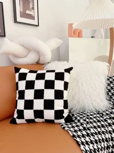 Modern black and white checkered throw pillow on a leather sofa for living room decor.